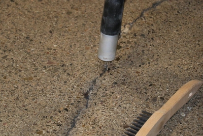 Flüssiger Epoxid-Rissfüller wird in einen Betonriss gegossen